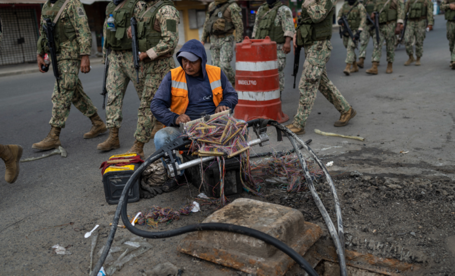 oldados marchan por Durán, Ecuador, mientras un trabajador repara cables de internet. Crédito: Associated Press